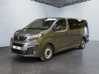 La camionnette argentée est garée dans une grande pièce au sol noir.