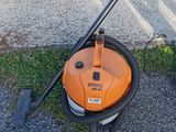 an orange and black vacuum cleaner sitting on top of a sidewalk next to a car