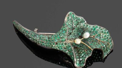 une image représentant une broche verte ornée d'une perle et de feuilles vertes