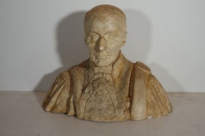 statue représentant le buste d'un homme en costume-cravate, posée sur une table