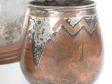 a pot with a design on it sitting next to a mirror