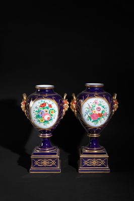pair of purple and gold vases with flowers on them against a black background