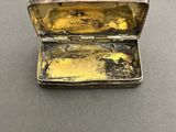 a small silver box with a yellow substance inside of it