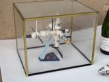 une petite maquette de station spatiale dans une vitrine, à côté d'une bouteille de vin