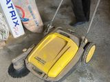 a man that is cleaning the floor with a lawn mower