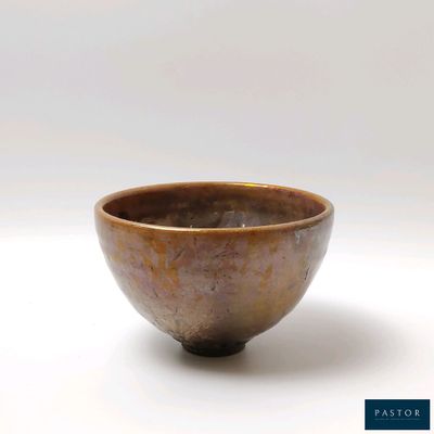 un petit bol marron posé sur une surface blanche