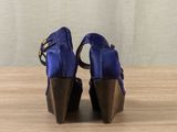the back view of a pair of blue high heeled shoes on a wooden table