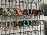 many bracelets hanging on a wire rack on the wall