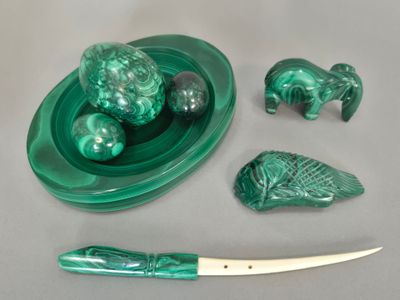 une assiette verte sur laquelle se trouvent un couteau, un bol de fruits et d'autres objets