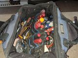 un sac rempli d'outils posé par terre à côté d'un ordinateur portable