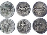 six ancient roman coins, one of which has a bird on it