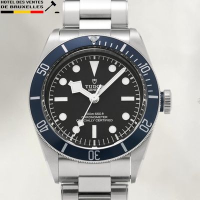 La montre est noire et argentée, avec un cadran à lunette bleue.