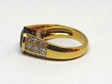 une image représentant une bague en or sertie d'une pierre noire entourée de diamants blancs