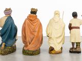 three figurines of people dressed in traditional clothing are standing in a row