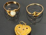 two gold rings and a heart shaped locke on a table