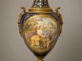 un grand vase orné d'une peinture, posé sur un socle