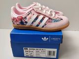 une paire de chaussures Adidas roses posée sur une boîte bleue