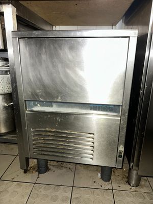 a small stainless steel refrigerator in a kitchen with a lot of dirty flooring