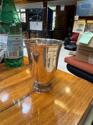 a silver cup sitting on a wooden table next to a bottle of water