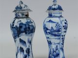 une paire de vases bleus et blancs avec couvercles, posés sur une surface blanche