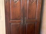 une armoire placée dans un coin de la pièce, avec une chaise devant