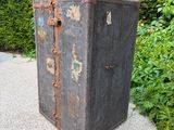 an old black suitcase sitting on a gravel path