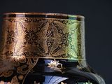 a black vase with a gold and blue design on it