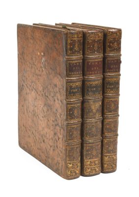 trois vieux livres sont empilés sur une surface blanche