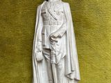 une statue représentant un homme avec une cape sur la tête