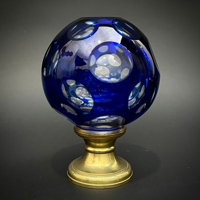 un vase en verre bleu avec un socle doré posé sur une table