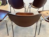 quatre fauteuils en cuir marron empilés les uns sur les autres dans une pièce