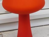 une table orange avec un piètement rouge, posée sur un rebord de fenêtre