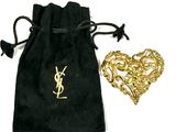 une pochette en velours noir ornée d'une broche en forme de cœur dorée et un sac en velours noir orné d'une broche en forme de cœur dorée