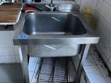 a sink in the corner of a kitchen with a lot of bottles on the counter