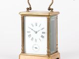 une petite horloge en laiton avec des chiffres romains sur le cadran