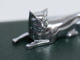 a silver cat figurine sitting on a green surface