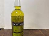 La bouteille de Chartreuse est posée sur une table en bois.