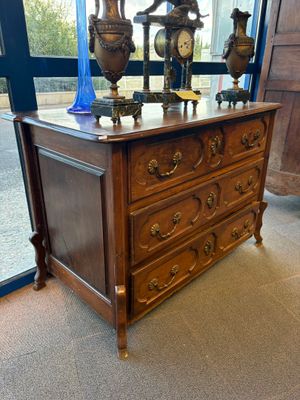 une commode sur laquelle est posée une horloge, devant une fenêtre