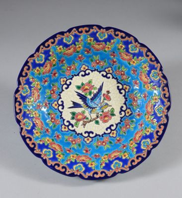 une image représentant une assiette bleue et rouge sur laquelle figure un oiseau