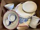 a cardboard box filled with dishes and cups and saucers