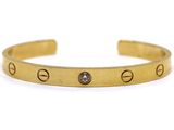 a close up of a gold bracelet with a diamond on it
