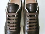 pair of black leather sneakers with white soles on a white surface