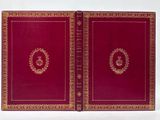 a red book with gold trim and a wreath on the cover