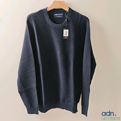 a blue sweater hanging on a hanger on a wall