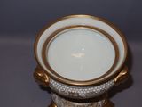 a white and gold vase with a gold rim on a table