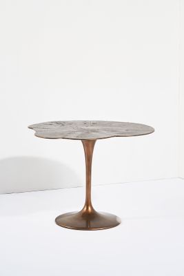 une table ronde avec un piètement en métal et un plateau en marbre
