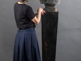 une femme debout à côté d'une statue représentant le buste d'un homme