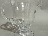a clear glass pitcher sitting on a white surface