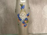 un vase en verre orné de fleurs, posé sur une étagère