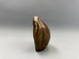 une image représentant une sculpture en bronze d'un oiseau posée sur une surface blanche